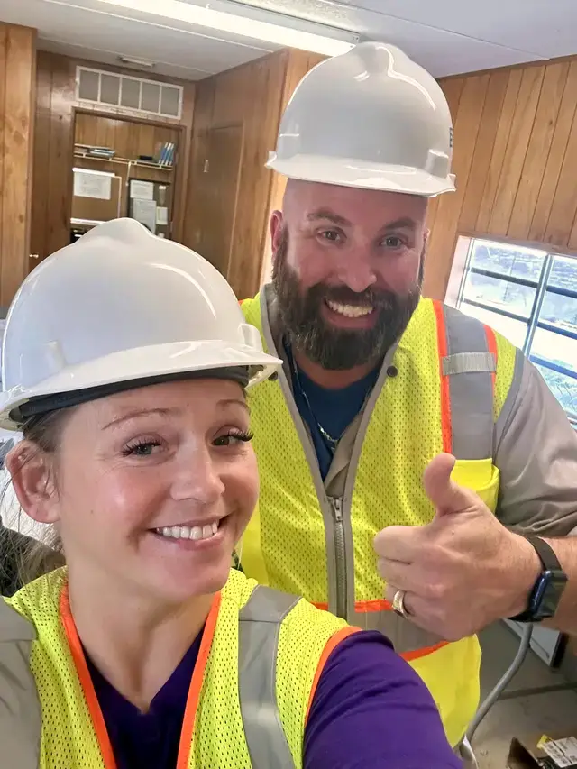 JJ and a team member in hard hats and safety vests on a new build