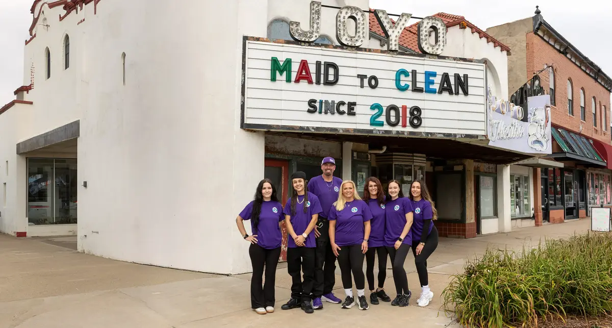 The Maid to Clean team in purple shirts under the JOYO marquee that reads Maid to Clean since 2018